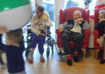 Young children from Rodmersham Nursery playing ball catch with residents from Woodstock Residential Care Home