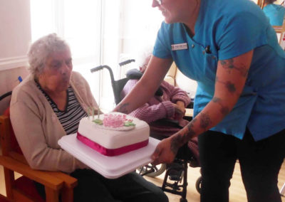 Resident blowing our her birthday cake candles at Edith turns 90 at Woodstock Residential Care Home