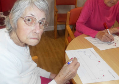 Resident at Woodstock Residential Care Home colouring a paper crown to celebrate the Queens birthday