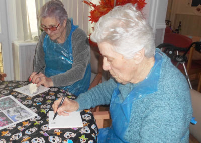 Two lady Woodstock residents sat at a table painting white tiles