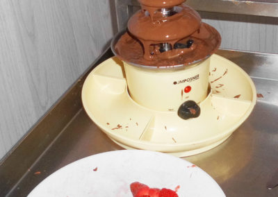 A chocolate fountain and a plate of fresh strawberries
