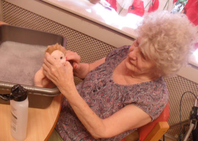 Lady resident cleaning a doll in a bowl of water