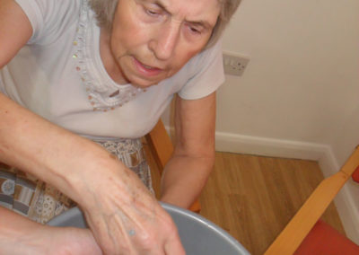 Lady with sand and water in a bowl, shaping it with moulds