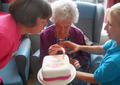 Lady resident receiving an iced birthday cake at Woodstock Residential Care Home