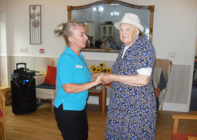 Staff member and lady resident dancing together at Woodstock Residential Care Home