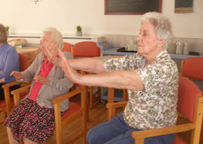 LAdy doing seated arm movements in a Tai Chi class