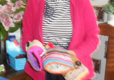 Lady posing with knitted twiddle muffs