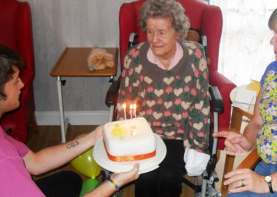 Lady resident receiving an iced birthday cake with candles