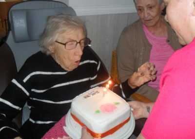 Female resident at Woodstock Residential Care Home blowing out candles on her birthday cake