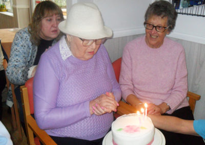 Resident at Woodstock Residential Care Home blowing out candles on her birthday cake