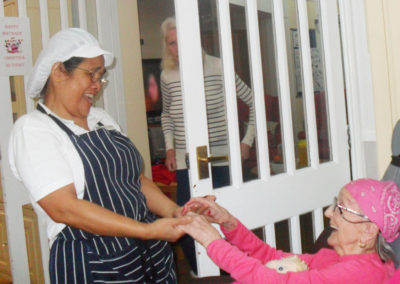 Cook and staff member holding hands and smiling at each other