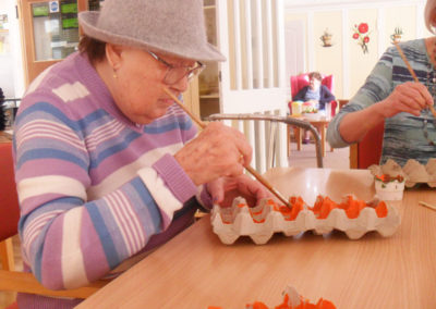 Resident at Woodstock painting an egg box for St David's Day crafts