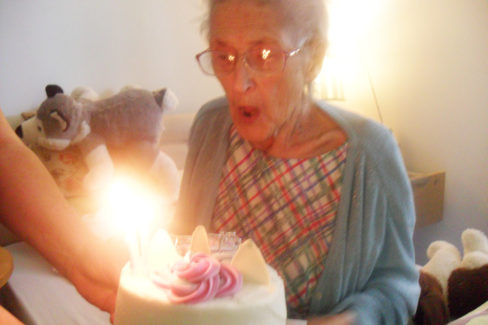 Resident Daphne blowing out the candles on her birthday cake at Woodstock Residential Care Home 