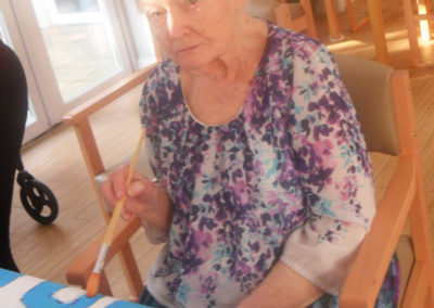 Lady resident at Woodstock Residential Care Home painting lettering on a sheet