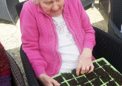 Lady resident planting seeds in the garden at Woodstock Residential Care Home