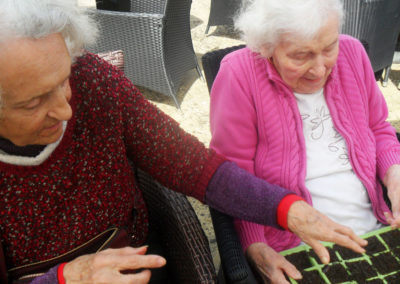 Two residents planting seeds in the garden at Woodstock Residential Care Home