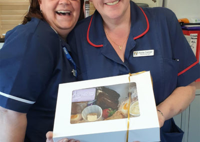 Manager and Deputy Manager at Woodstock showing off an afternoon tea box