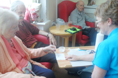 Staff and residents gluing photos into albums at Woodstock Residential Care Home
