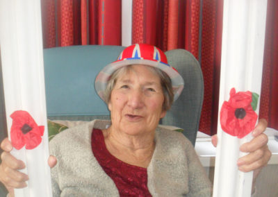 Woodstock Residential Care Home resident smiling at the camera with a poppy photo frame