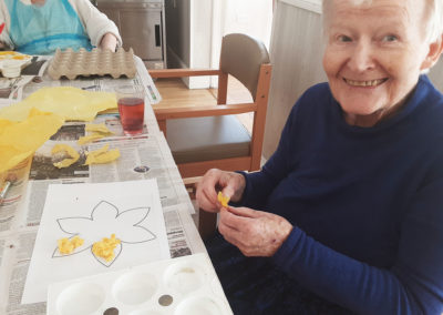 Resident adding tissue paper to her paper daffodil picture at Woodstock Residential Care Home