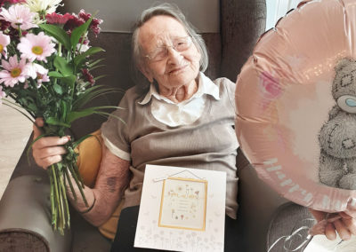 Resident with flowers and a balloon on Mother's Day at Woodstock Residential Care Home