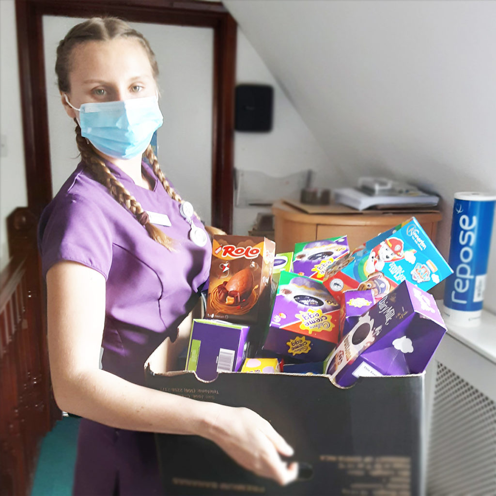 Staff member at Woodstock Residential Care Home holding a box of Easter eggs donated by Morrisons