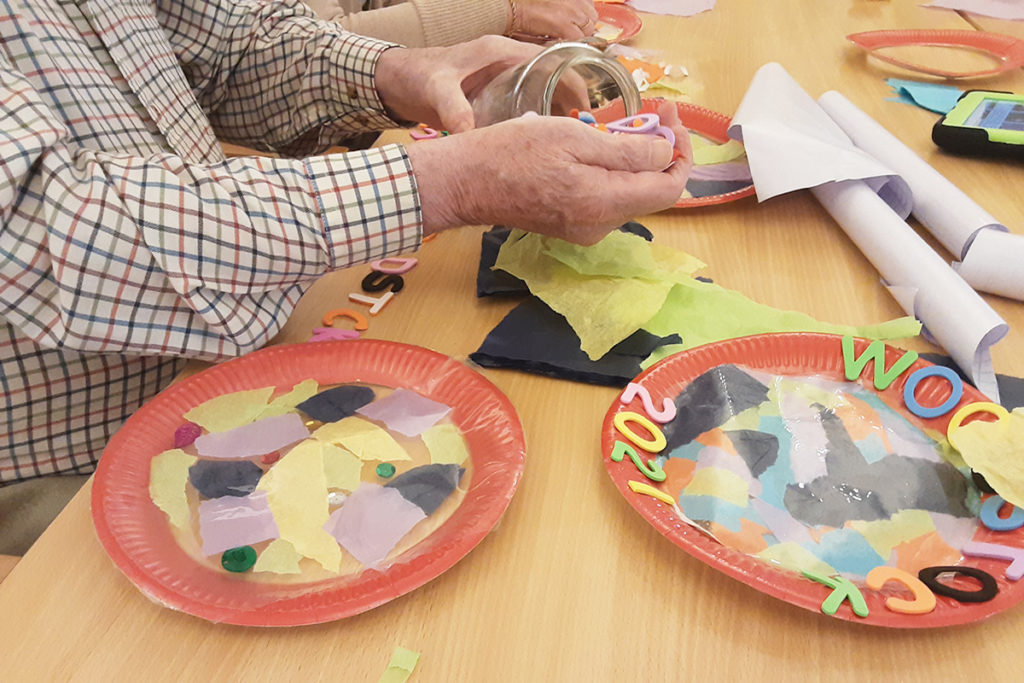 Resident decorating a paper plate suncatcher at Woodstock Residential Care Home