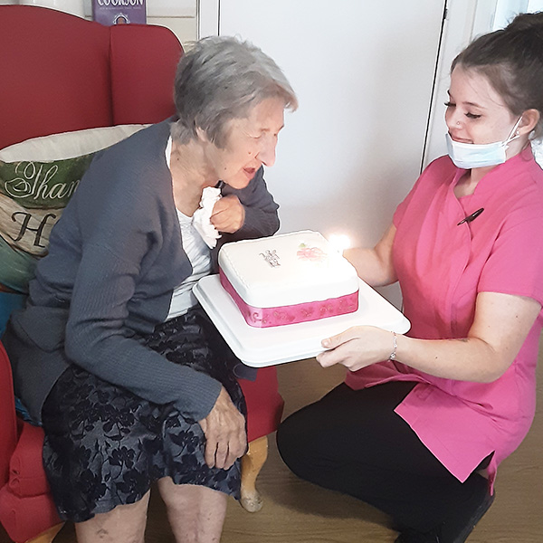 Woodstock Residential Care Home resident blowing out the candles on her birthday cake
