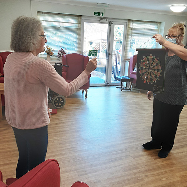 Lady resident playing darts at Woodstock Residential Care Home